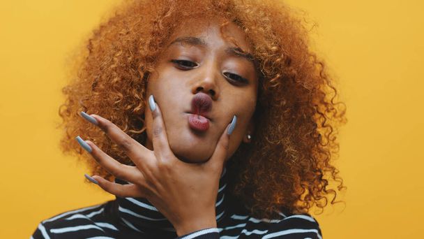 Jovem negra afro-americana com cabelos encaracolados e unhas compridas fazendo caretas  - Foto, Imagem