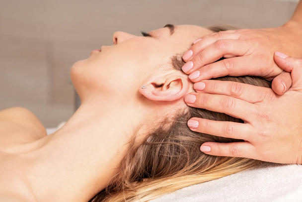 Young woman receiving head massage by hands of beautician in spa beauty center - Foto, immagini