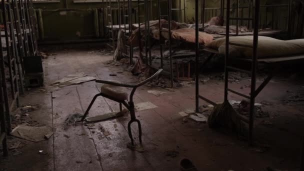 2020 yılında Ukrayna 'nın Çernobil sınırlama bölgesindeki Pripyat hayalet kasabasında terk edilmiş bir anaokulunda bebek karyolası ve çocuk bisikleti. - Video, Çekim