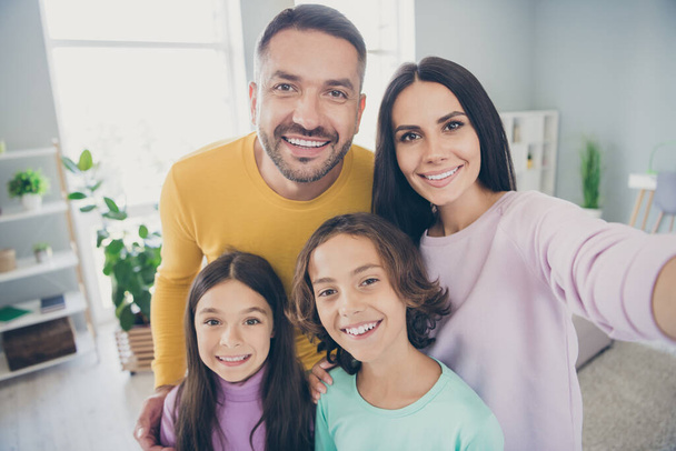 Photo of full family four people mommy take selfie hug beaming smile wear colorful sweater in living room indoors - Фото, изображение