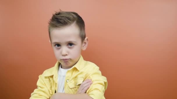 Estudio retrato de niño travieso haciendo pucheros labios, sintiéndose ofendido, alejándose de la cámara - Metraje, vídeo