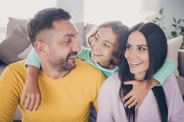 Photo of full family three people small boy embrace parents shiny smile wear colorful pullover in living room indoors - Foto, Imagem
