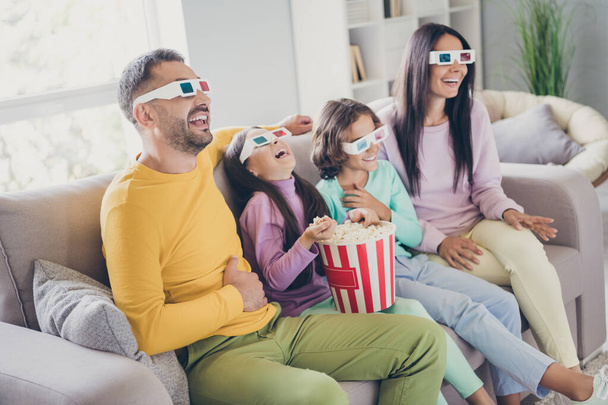 Photo of full big family four members sit sofa hold pop corn bucket laugh wear 3d glasses colorful sweater pants in living room indoors - Foto, immagini