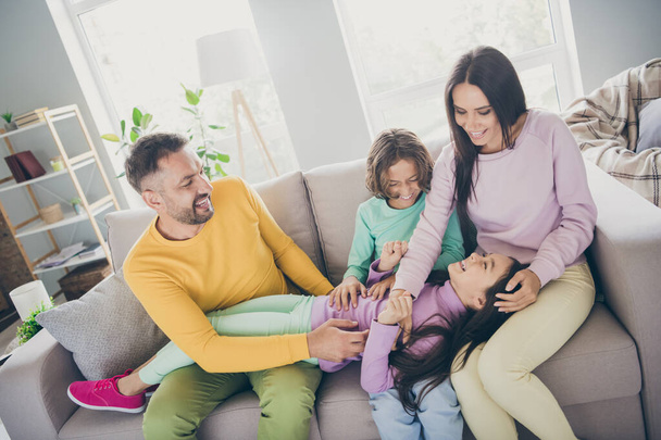 Photo of full big family four members daughter lay knee pillow wear colorful pullover trousers in living room indoors - 写真・画像