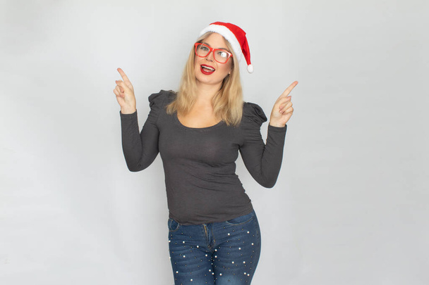 Woman in santa hat and red glasses posing isolated on white background. Caucasian girl happy looking at camera. - Zdjęcie, obraz