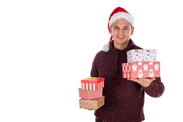 Young caucasian man with Santa hat is holding christmas gifts on isolated background - Fotoğraf, Görsel