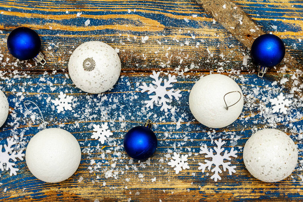 Weihnachten oder Neujahr festlicher Hintergrund. Weiße und blaue Weihnachtskugeln, Schneeflocken und verstreut glitzernder Kunstschnee. Vintage-Holzbretter in Blautönen, Draufsicht - Foto, Bild
