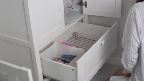 Mamá pone las cosas limpiamente en el armario de su pequeña hija - Metraje, vídeo