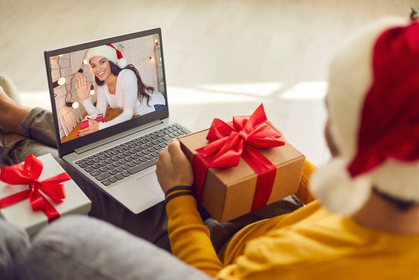 Man with laptop holding present and video calling his girlfriend on Christmas holidays - Fotoğraf, Görsel