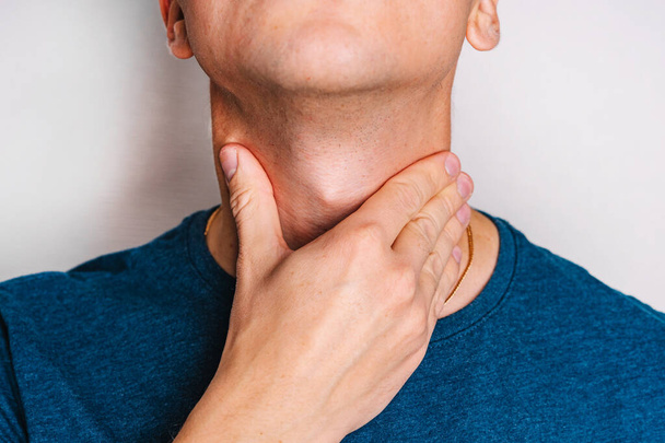 Чоловік відчуває біль у горлі і перевіряє мигдалини і лімфатичні вузли
. - Фото, зображення