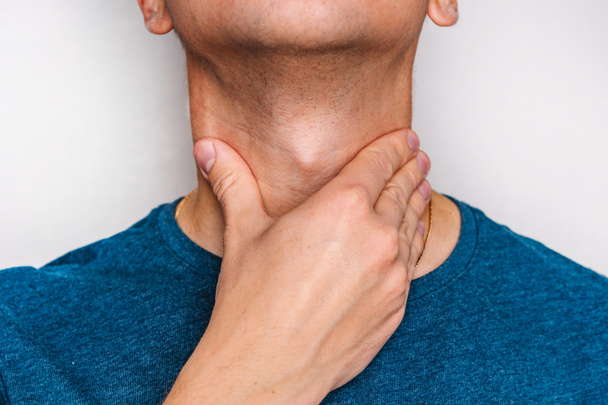 Мужчина чувствует боль в горле и проверяет миндалины и лимфоузлы. - Фото, изображение