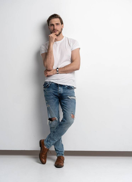 Full length studio portrait of casual young man in jeans and shirt. Isolated on white background. - Фото, зображення