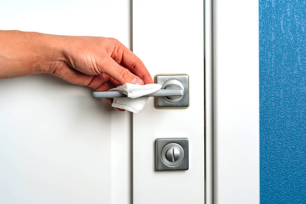 Pulisce a mano la maniglia della porta con un panno disinfettante antibatterico, prevenzione del coronavirus - Foto, immagini