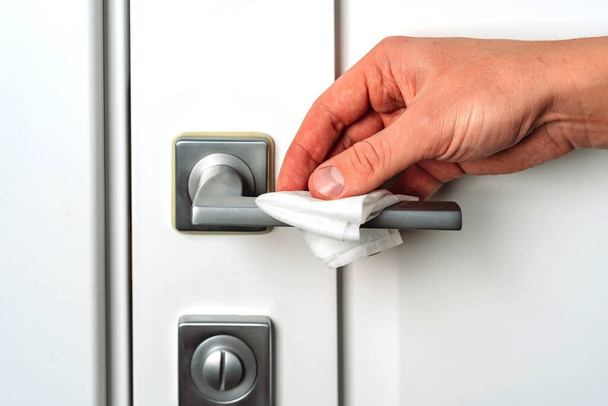Hand wipes the door handle with an antibacterial disinfecting cloth, prevention of coronavirus - Foto, immagini