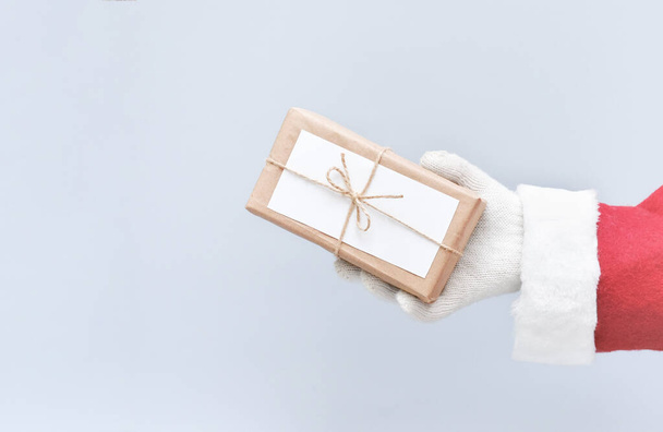 Die Hand des Weihnachtsmannes hält ein in Bastelpapier eingewickeltes Weihnachtsgeschenk. Zero Waste Weihnachten. Ökologische und nachhaltige Geschenke. Handgemachte Verpackung. Kopierraum. Sicht der Ernte - Foto, Bild
