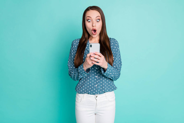 Photo of astonished girl read social media posts on cellphone shout isolated over turquoise color background - Foto, afbeelding
