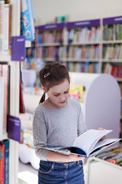 school girl in library choosing books. - Foto, Bild
