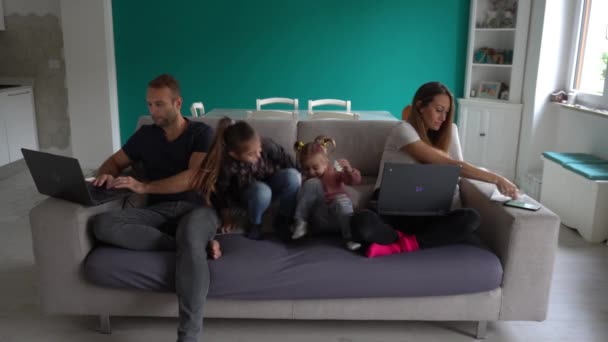 Evropa, Itálie, Milán - rodinný životní styl doma během epidemie zamykání koronaviru Covid-19 - Děti si hrají v obývacím pokoji a rodiče chytře pracují - Lombardie červená zóna - Záběry, video