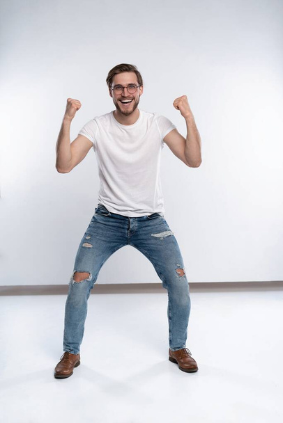 Happy winner. Happy young handsome man gesturing and keeping mouth open while standing against white background. - Φωτογραφία, εικόνα