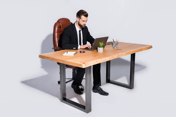 Full body photo of handsome business guy notebook table chatting colleagues read corporate report wear black blazer shirt pants shoes costume sitting chair isolated grey background - Foto, imagen