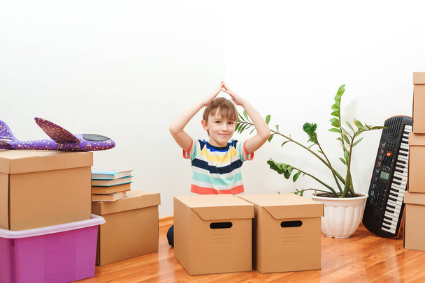 Cute little boy in new house. Housing a young family with kid. Family moves into a new apartment. Boy playing in their new apartment. Cute kid helping unpacking boxes. - Photo, Image
