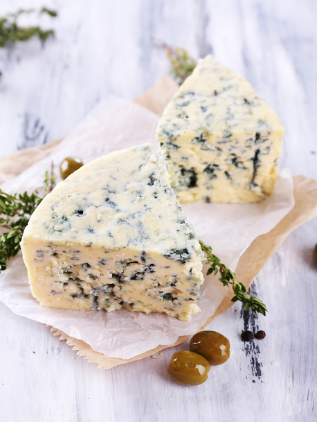 Tasty blue cheese with thyme and olives on wooden table - Photo, image