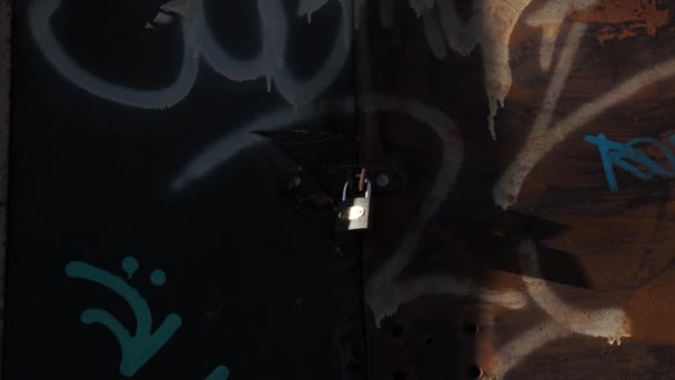 Ein Vorhängeschloss an einigen alten Türen mit Graffiti angebracht. - Filmmaterial, Video