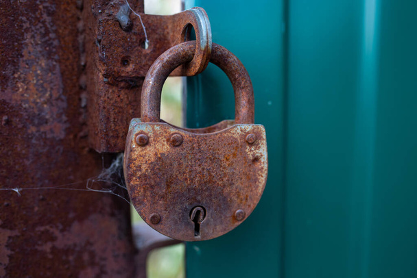 A rusty lock without a key hangs on a metal fence. Security concept. Selective focus. Copy space - Photo, Image