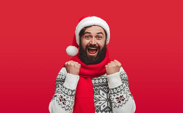 Excited bearded man in Santa hat celebrating victory - Foto, immagini