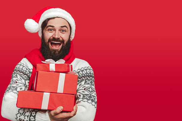 Delighted hipster man carrying stack of Christmas gifts - Foto, Imagem