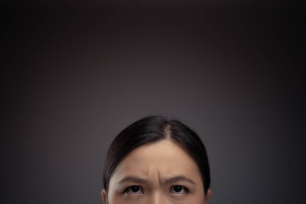 Gros plan de femme asiatique confus regarder vers le haut avec l'espace de copie. Isolé sur fond. - Photo, image