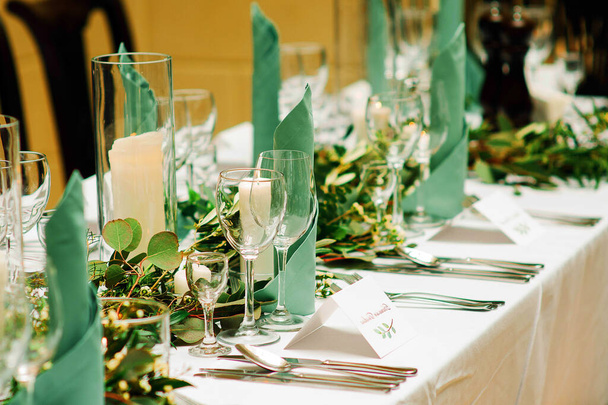 Elegant table setting at the restaurant. Wedding banquet with floral decoration on table, cards, glasses and cutlery closeup - Photo, Image