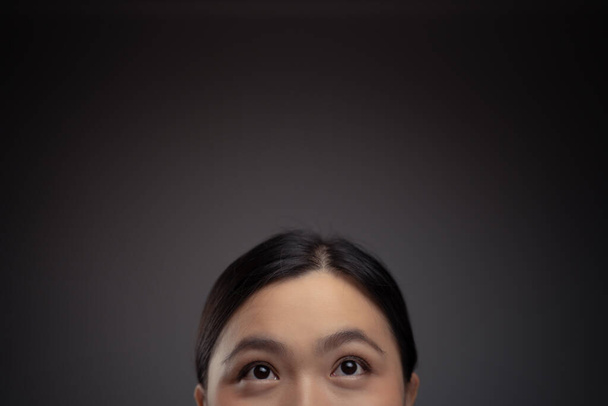 Közelkép egy boldog ázsiai nőről, aki felnéz a fénymásolótérrel. Elkülönítve a háttérben. - Fotó, kép