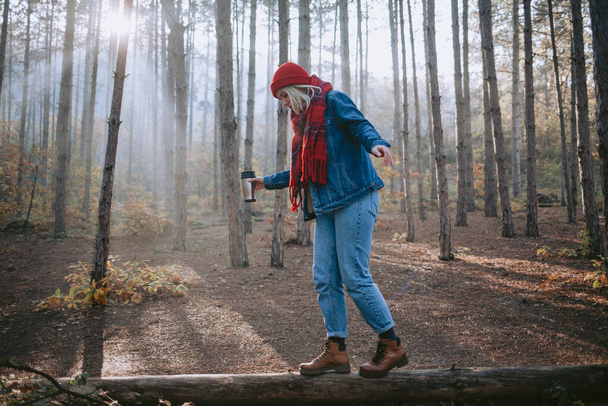 Woman walking on a fallen log in the forest - Фото, изображение