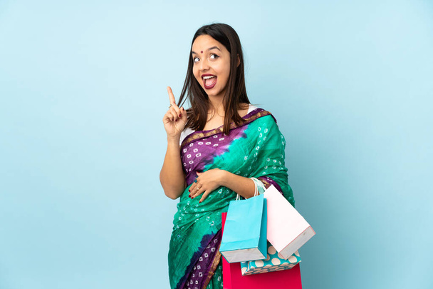 Mulher indiana jovem com sacos de compras com a intenção de realizar a solução, levantando um dedo para cima - Foto, Imagem