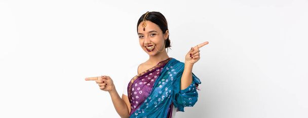 Beyaz arka planda izole edilmiş genç Hintli kadın parmak uçlarını işaret ediyor ve mutlu. - Fotoğraf, Görsel