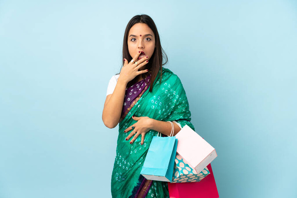 Молодая индианка с сумками удивлена и шокирована, глядя направо - Фото, изображение