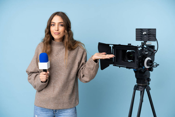 Reportera joven sosteniendo un micrófono y reportando noticias que tienen dudas con expresión de cara confusa - Foto, imagen