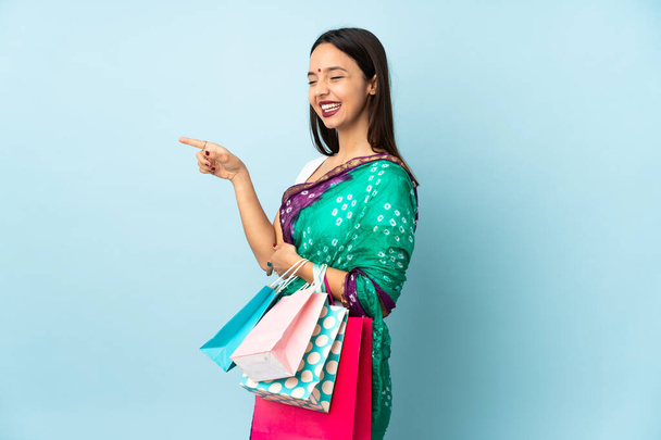 Jovem indiana com sacos de compras apontando o dedo para o lado e apresentando um produto - Foto, Imagem