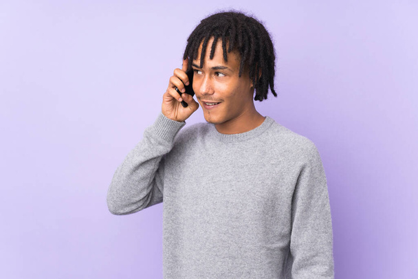 Young african american man isolated on purple background keeping a conversation with the mobile phone with someone - Φωτογραφία, εικόνα