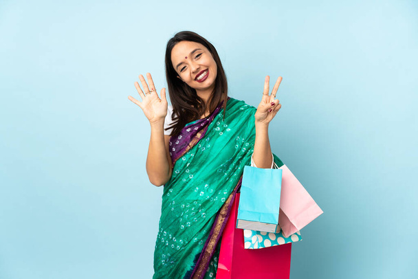Junge Inderin mit Einkaufstüten, die mit den Fingern sieben zählen - Foto, Bild