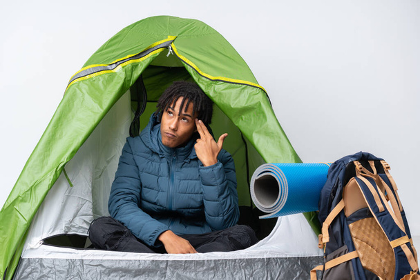 Young african american man inside a camping green tent with problems making suicide gesture - Zdjęcie, obraz
