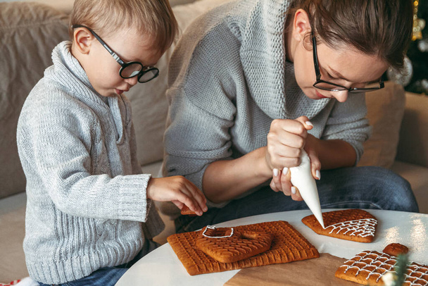 A Little boy with mom decorate christmas gingerbread house together - Foto, immagini