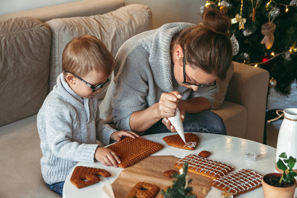 A Little boy with mom decorate christmas gingerbread house together - Zdjęcie, obraz