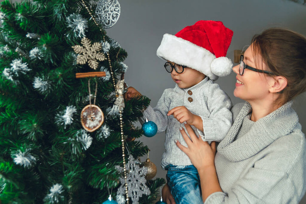 Mom and her child decorate the christmas tree together - Valokuva, kuva