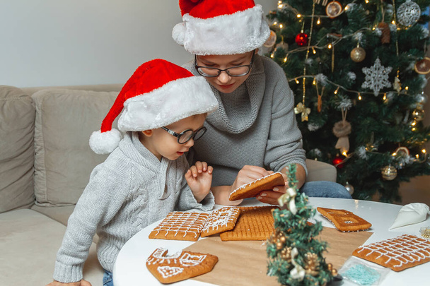 A Little boy with mom decorate christmas gingerbread house together - Фото, зображення