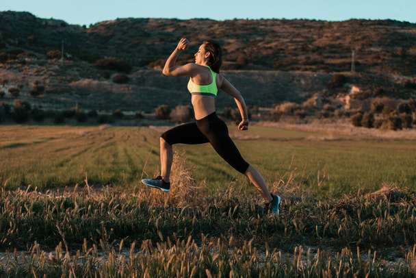 Una corredora corriendo por el prado de primavera. Entrenamiento en una naturaleza. - Foto, imagen