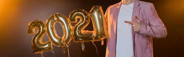 cropped view of man pointing with finger at 2021 numbers balloons on black, banner - Fotó, kép