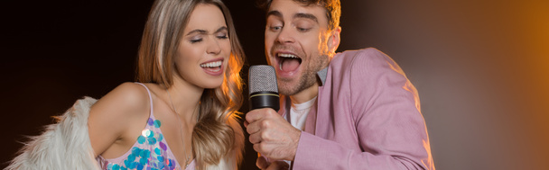 man and blonde woman singing while holding microphone on black, banner - Photo, Image