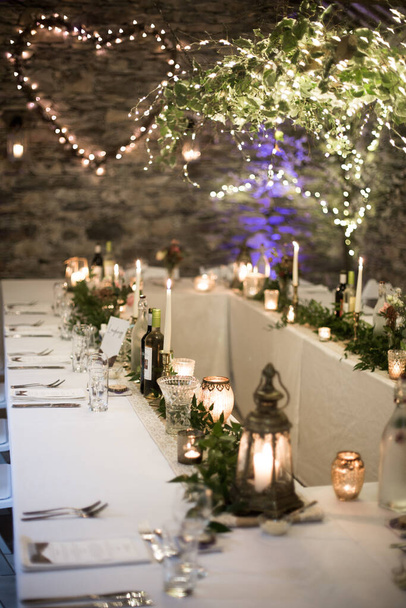 Çiçekler ve mumlarla süslenmiş bir ahırda düğün masası. - Fotoğraf, Görsel